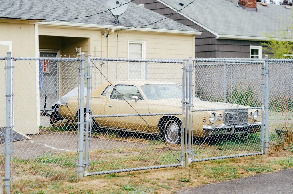 white and brown sedan parked beside white metal fence during daytime